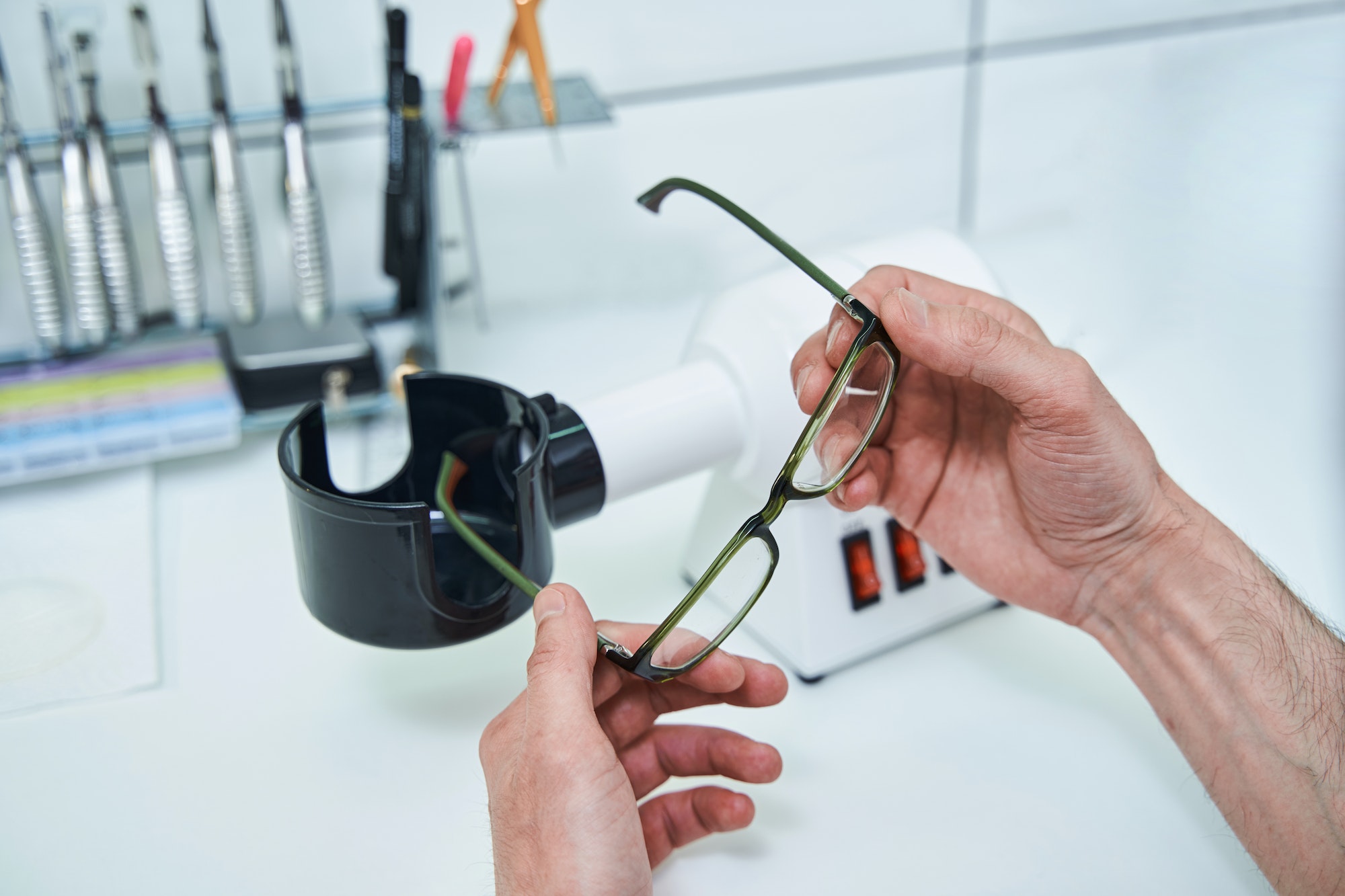 Male optician hands holding glasses with green frame
